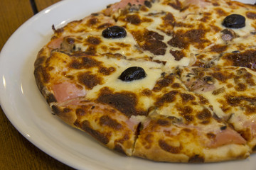 tasty pizza with mushrooms, cheese, olives and meat on the plate 