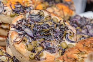 Traditional Italian focaccia with herbs onions and olives sold at Borough Market in London, UK