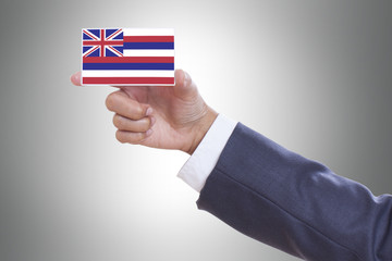 Businessman hand holding a business card with Hawaii flag