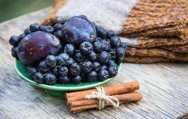 Aronia melanocarpa (Black chokeberry) and plums on wooden table. Home atmosphere. Autumn concept. Autumn harvest. Knitten things