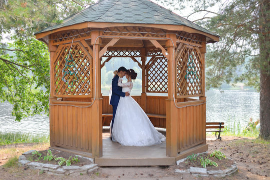 Bride and groom kissing insude summer house