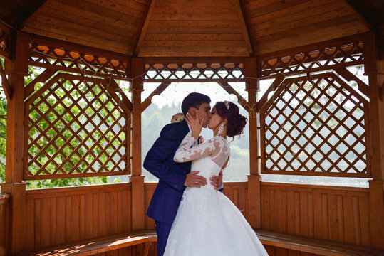 Bride and groom kissing insude summer house
