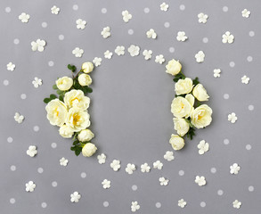 Frame of white roses (Burnet double white, shrub rose) and flowers viburnum with little white circles on a gray background with space for text. Flat lay