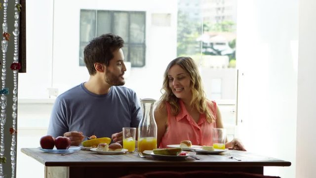 Young couple kissing and eating fruits and breakfast