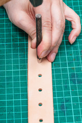 punching holes in new belt with hole punch