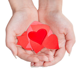 heart above pile of paper hearts on female palms