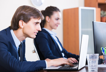 Fototapeta premium Two young managers using laptop at work