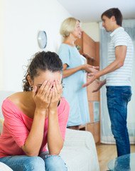 Upset girl watching her husband and senior mother fighting