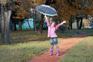 Happy little girl with umbrella in park autumn season