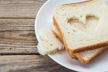 A stack of white bread slices on a plate on a wooden table.