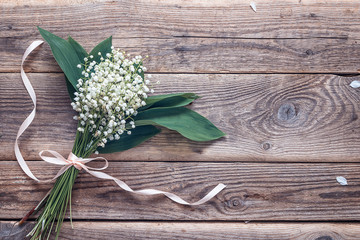 Bouquet of lily of the valley on the old wooden background. Plac