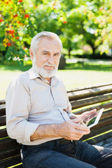 Senior man using digital tablet in a park, active lifestyle concept