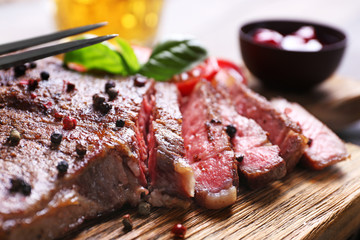 Grilled steak with tomatoes and sauce on cutting board, closeup