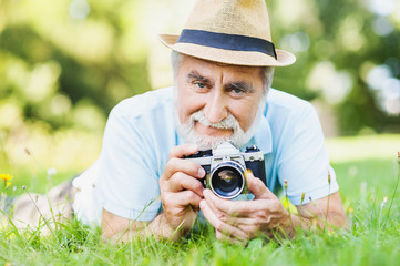 Closeup portrait of a smiling funny senior man taking pictures, active lifestyle concept