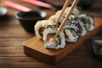 Tasty sushi roll with wooden chopsticks, closeup