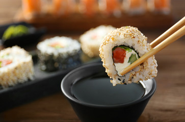 Tasty sushi roll with wooden chopsticks and sauce in bowl