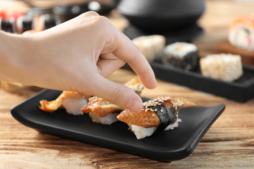 Female hand holding delicious fish sushi, closeup