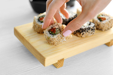 Female hand holding delicious sushi rolls on table © Africa Studio