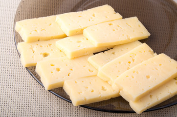 Pieces of dry yellow hard cheese on a plate closeup