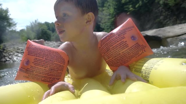 Young Boy Having Fun on Inflatable Mattress in the Mountain River