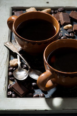 Obraz na płótnie Canvas cups of black coffee, sugar and chocolate on a blackboard