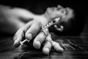 syringe in overdose asian male drug addict hand, BW photo
