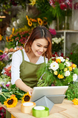 Vietnamese young florist with bouquet working on tablet