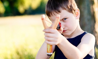 Little boy playing with slingshot