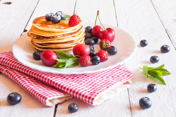 Pancakes with berries on wooden table
