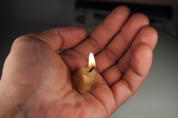 Горящий огарок свечи на ладони