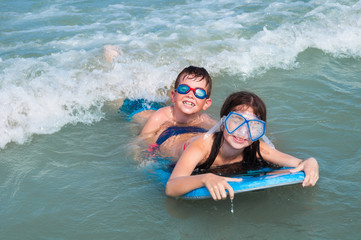 Two kids swimming with surf board