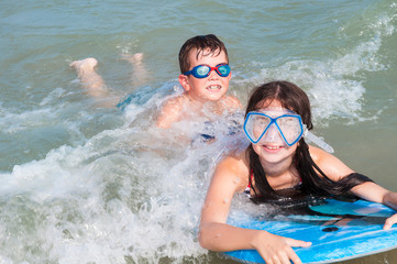 Two kids swimming with surf board