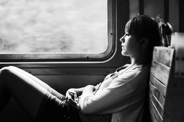 Girl on train. Listen to music. Travel in transport. Sad mood, loneliness. Black and white photo