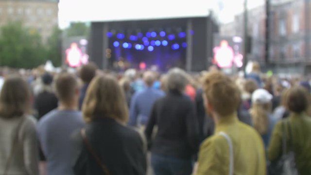 Crowd watching a artist that perform on a stage. Out of focus