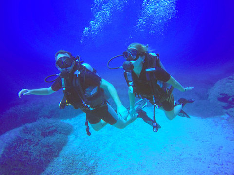 A scuba diver couple applying the buddy system. View of the scuba diver gear, fins and bubbles underwater in the deep blue sea of Protaras, Cyprus, swimming. © f8grapher
