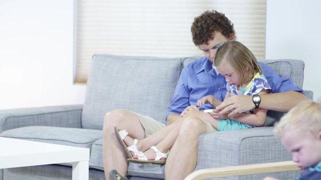 Pan up to father teaching daughter how to use cellphone