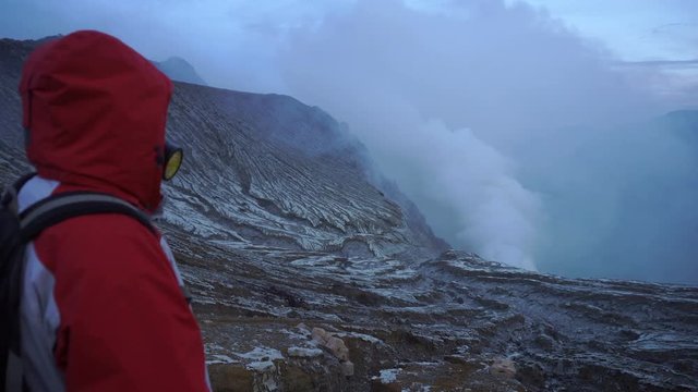 Backpacker male traveler in respirator mask standing at crater rim of Ijen volcano in Indonesia. Young man living active lifestyle