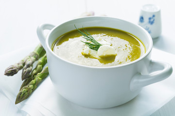 Bowl of asparagus soup topped with fresh cream and dill