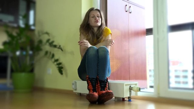 Young woman put,cap on sitting on cold radiator