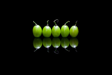 Five grapes on black reflective background