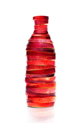 Bottle made from red sliced apples on white