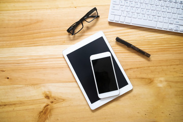 office table with computer keyboard, glasses, tablet pc and smartphone. copy space