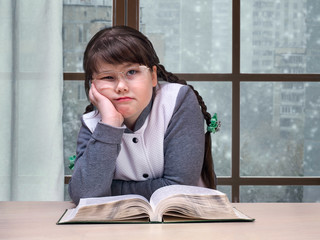 Girl with the book is sad. Outside the window, snow, winter. The concept of sadness, loneliness, adolescence, overweight, complexity