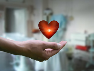 The hand of man. Glowing red heart. Background operating hospital. The concept of health, healing,...