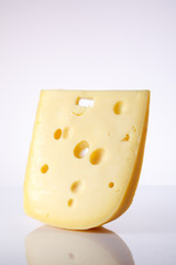 a piece of Swiss cheese with holes large triangular-shaped forms on a gray background with a gradient. food background. one piece of European cheese