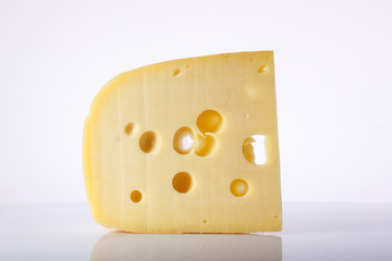 a piece of cheese with the large holes on a light background with a gradient. Food color image. Austrian semi-hard cheese