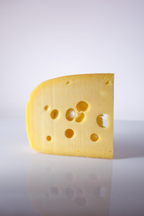 a piece of Swiss cheese with holes large triangular-shaped forms on a gray background with a gradient. food background. one piece of European cheese