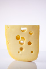 milk product. piece  cheese with big holes.a piece of cheese with the large holes on a light background with a gradient. alpinland.
