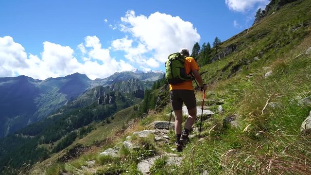 Hiker along a path in Valsesia, in the Italian Alps, on a sunny day