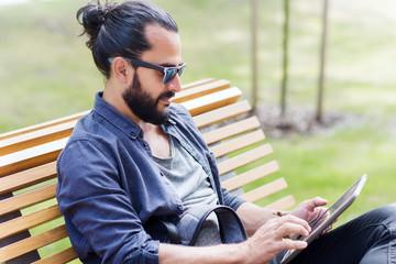 Fototapeta premium man with tablet pc sitting on city street bench